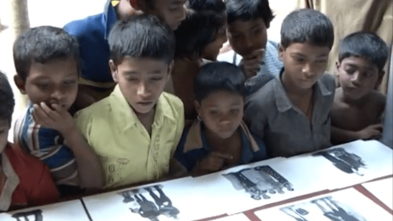 Niños indios mirando fotos sobre una mesa.