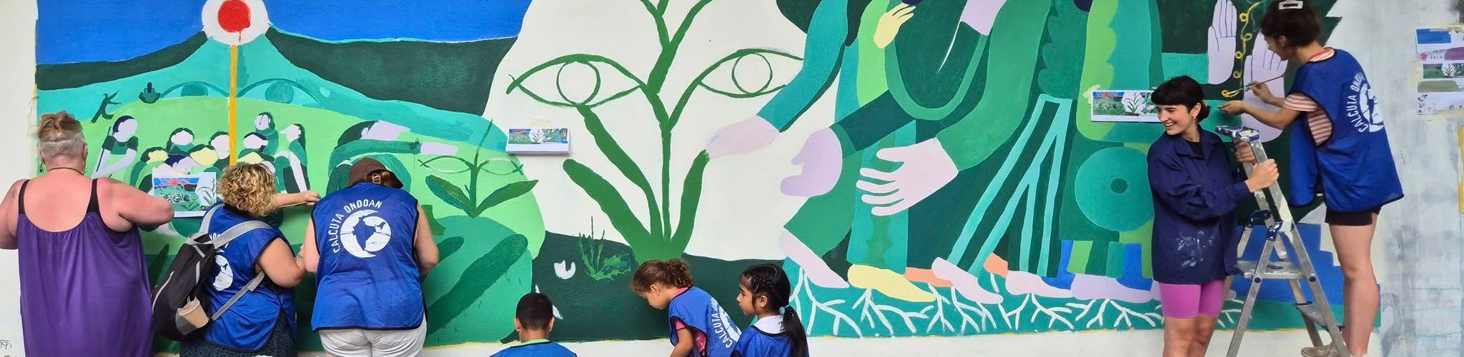 Imagen de niños, niñas y personas adultas voluntarias de Calcuta Ondoan pintando un mural