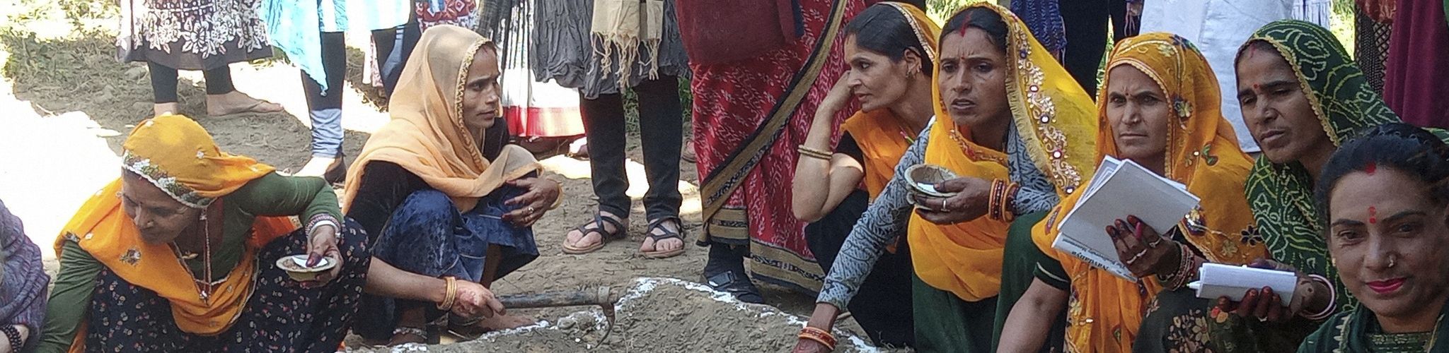 Calcuta ondoan sección actúa cabecera Mujeres Indias reunidas, agachadas y con azadas en las manos para la sección de Actúa con Calcuta Ondoan