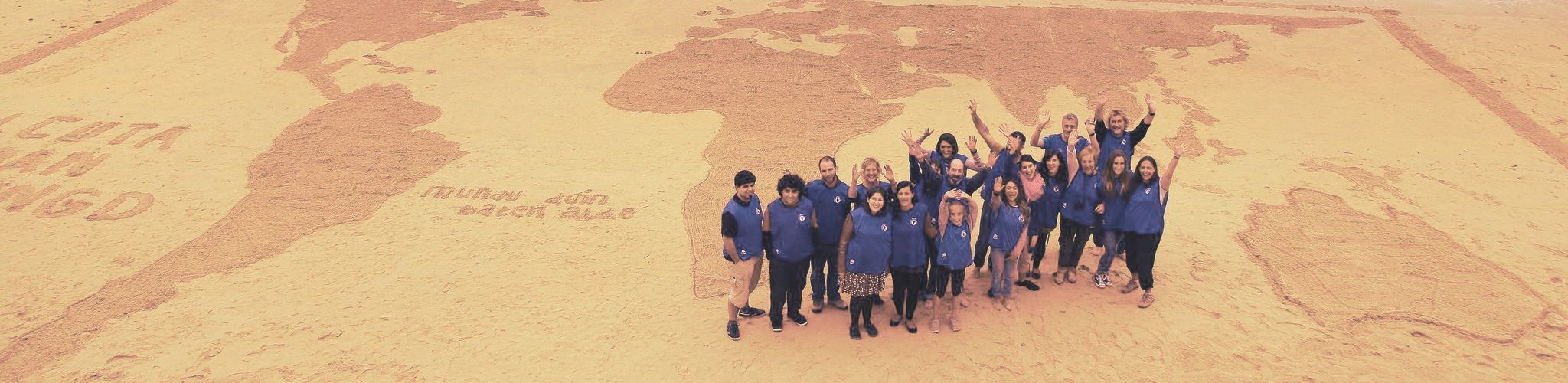 calcuta-ondoan-socixs-cabecera Grupo de voluntarios y voluntarias de Calcuta Ondoan ante un dibujo reivindicativo hecho en la arena de la playa de San Sebastián